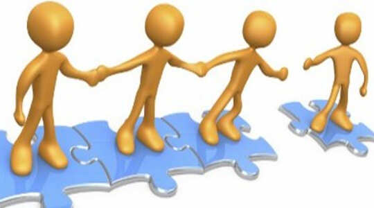 Caring is a Natural Reflex stick figures standing on joined puzzle pieces holding hands and reaching out to another figure on a separate puzzle piece