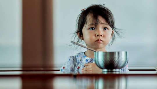 Why You Shouldn't Pressure A Picky Eater unhappy child sitting in front of a bowl of food