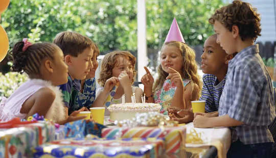 Why Kids Are Nervous About Ditching Masks children at a table around a birthday cake