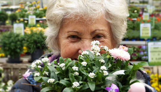 How To Keep Your Brain Working Well As You Age photo of an older woman with white hair behind a bouquet of flowers