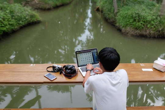 Visualizing A New Economy and a New Way of Living a young boy on a ship with his laptop open, and a camera and cell phone next to him.