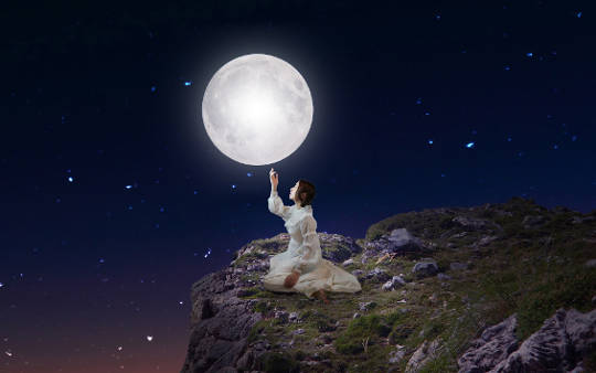 woman sitting under the full moon and stars