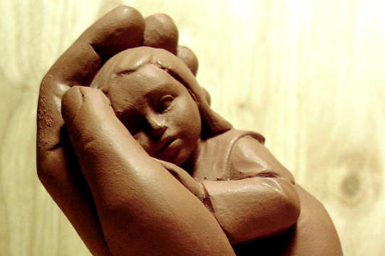 Eating Healing Clay for Detoxification and Protection a clay sculpture of a child being held in a supportive hand