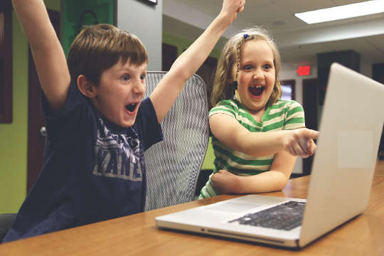Looking Back and Celebrating Your Successes two children in front of a computer celebrating a success hands up in the air and with big smiels