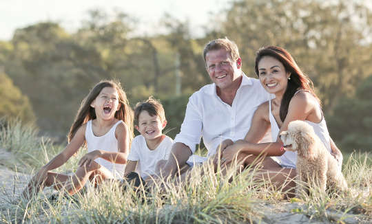 Teach Your Children Well a joyful family sitting together outside in an meadow