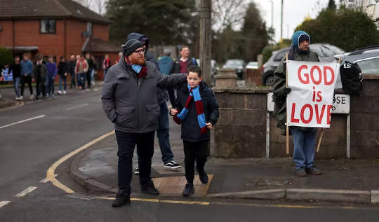 How Sports Became the New Religion - A 200 Year-old Story sports fanS on the way to a game, bystander holding a sign GOD IS LOVE