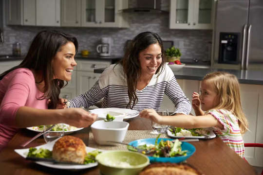 3 children sharing a meal and laughing around the table