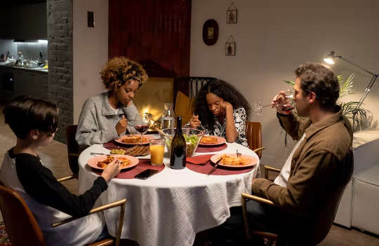 5 Realistic Tips to Ease the Pressure about Family Meals family sitting around a table eating