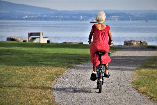 Reinventing Yourself in Retirement with a New Life Purpose a senior woman with white hair and a red dress riding a bicycle
