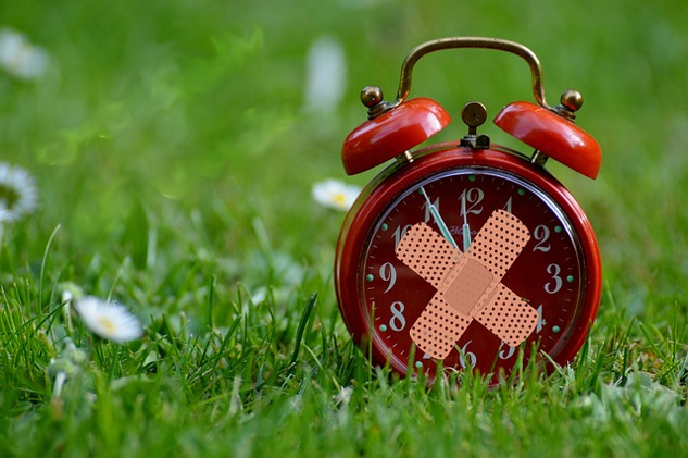 Healing Our Past and Living Forwards an old-style alarm clock with two bandaids over the face in the shape of an X
