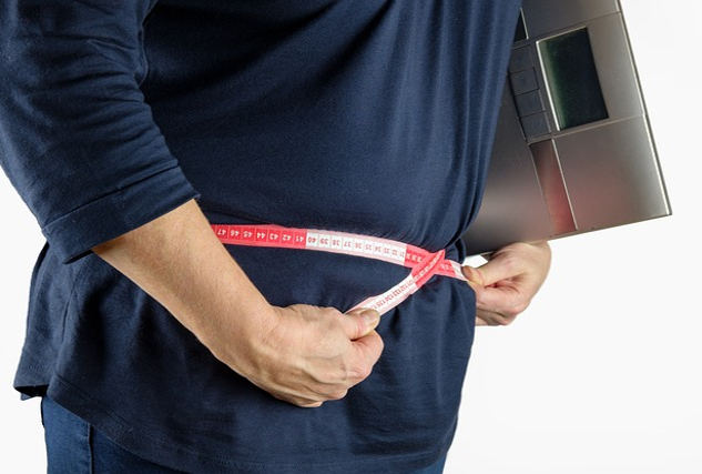 Girl, How Did We Get Here? Fat Shaming vs Self-Love a person measuring themselves around the waist while holding a digital scale under their arm