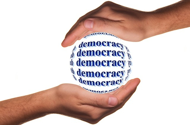Beyond Politics: 18 Reasons Trump Should Not Be President two hands protectively holding a globe named Democracy