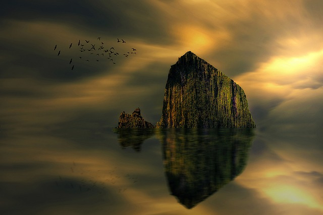 Ways to Connect with Your Higher Self a big rock or boulder jutting out of the water and being reflected in the calm usrface of the lake
