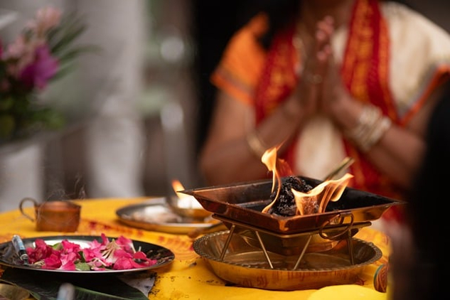 How Buddhism Explains the Illusion of Life a person in meditation in front of a bowl of flower petals and a bowl of fire