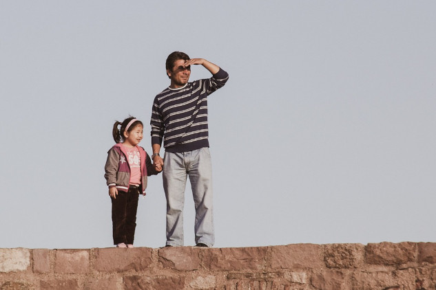 An American Dream for Our Times a father and daughter standing on a stone wall with the father looking into the distance