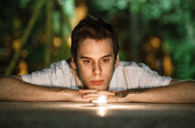 How to Optimize Your Sleep Based on Your Sleep Personality a young man laying down staring into a candle flame