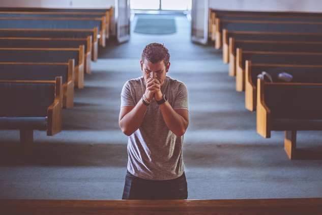 A man kneeling in a church praying. Image by Pexels from Pixabay. Is God Bipolar?